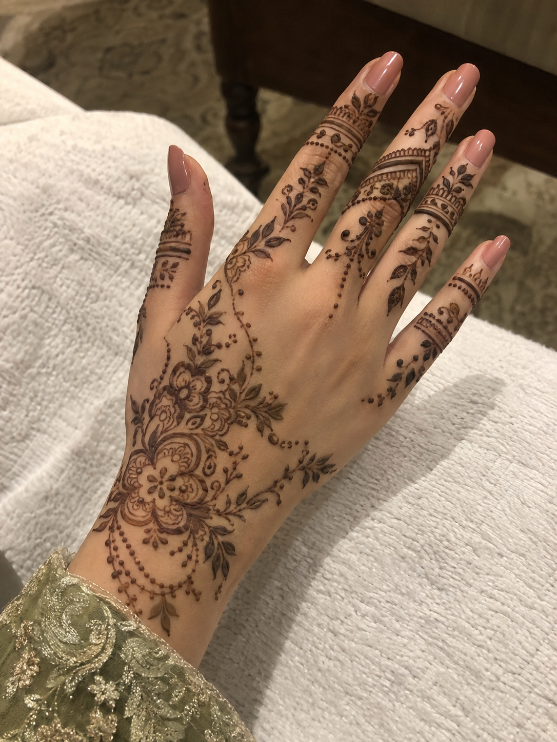 Fine floral mehedi trailing across a hand on soft white fabric
